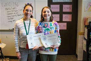 margaret smiling with teacher and holding two certificates